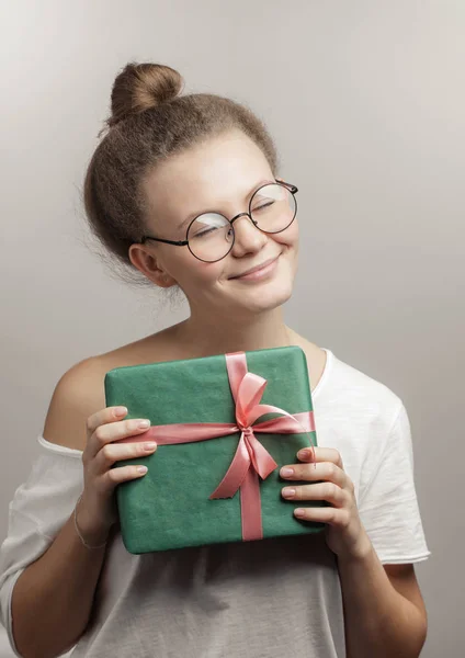 Hermosa chica con los ojos cerrados está sosteniendo una caja de regalo aislado —  Fotos de Stock