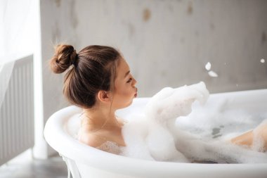 Genç güzel kız banyoda köpük ile oynarken