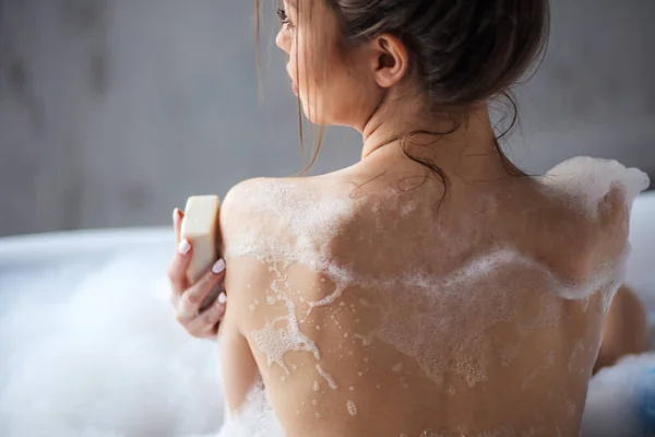 Mince belle femme avec un corps parfait assis dans la baignoire et en utilisant le savon — Photo