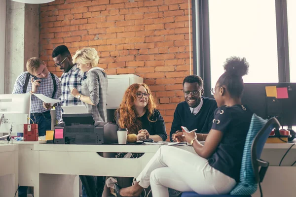 Active Caucasian red-haired woman and Arican man having a conversation with African nice woman