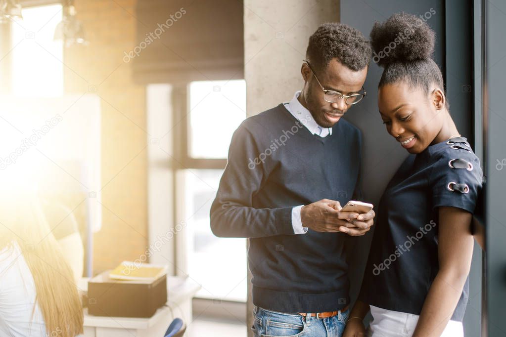 smiling black female and male texting sms message on smart phone