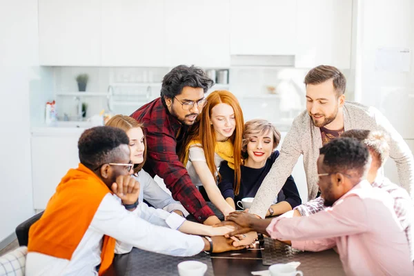 Diverse junge attraktive Menschen legen Hand an den Tisch — Stockfoto