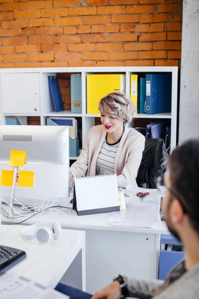 Красивая офисная работница, работающая за компьютером перед коллегой — стоковое фото