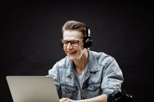 Glimlachende man luisteren naar muziek tijdens het spelen van games in de notebook — Stockfoto