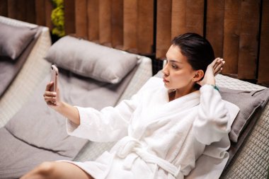 Loung üzerinde yalan beyaz bornoz giyen genç beauitiful kadın