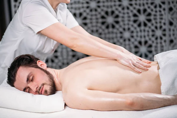 Aangename dark-haired kerel krijgt massage voor de rug — Stockfoto