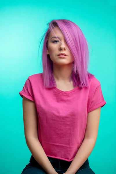 Muchacha atractiva con el pelo rosa, vestida con un paño rosa casual sobre fondo azul . — Foto de Stock