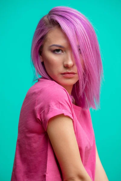 Muchacha atractiva con el pelo rosa, vestida con un paño rosa casual sobre fondo azul . — Foto de Stock