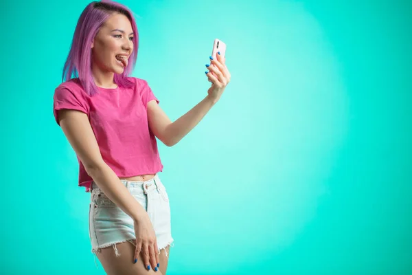 Mujer sonriente haciendo foto selfie en el teléfono inteligente aislado sobre un fondo azul — Foto de Stock