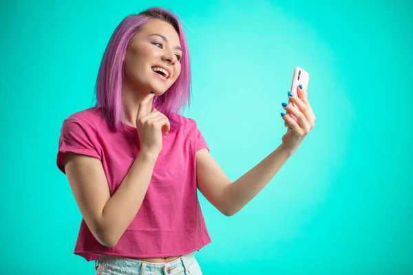 Mujer sonriente haciendo foto selfie en el teléfono inteligente aislado sobre un fondo azul — Foto de Stock