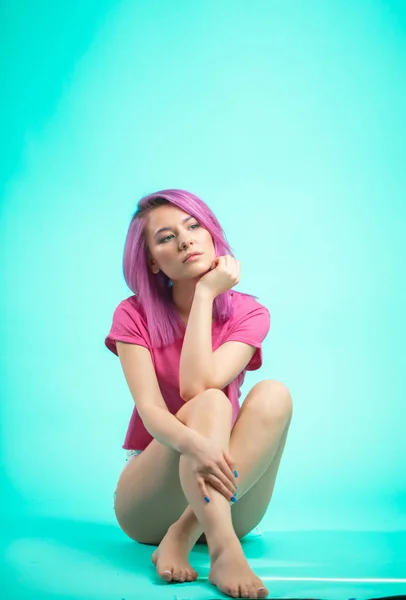 Jovem brilhante menina bonita com cabelo de cor rosa sentado no chão — Fotografia de Stock