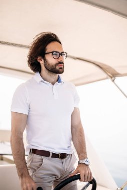 Motorlu teknesini süren yakışıklı sakallı denizci.