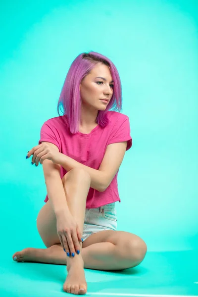 bright young beautiful girl with pink colored hair sitting on the floor