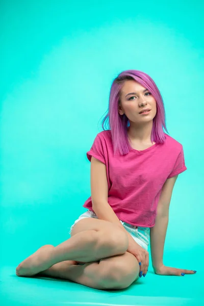 Helle junge schöne Mädchen mit rosafarbenen Haaren auf dem Boden sitzend — Stockfoto