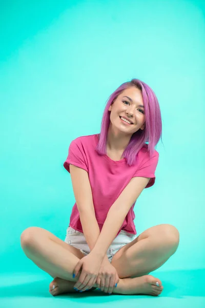 Student sitzt im Studio. junges Mädchen mit glattem rosa Haar sitzt auf dem Boden. — Stockfoto