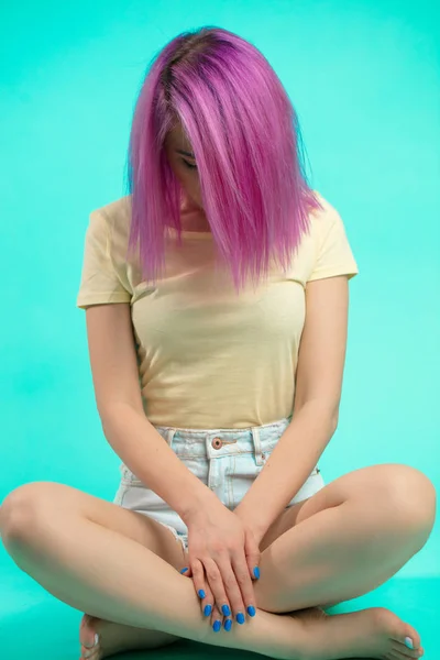 スタジオで座っている学生。床に座ってまっすぐピンクの髪を持つ少女. — ストック写真