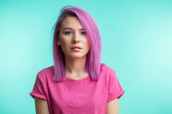 Attraente ragazza con i capelli rosa, vestita in tessuto rosa casual su sfondo blu . — Foto Stock