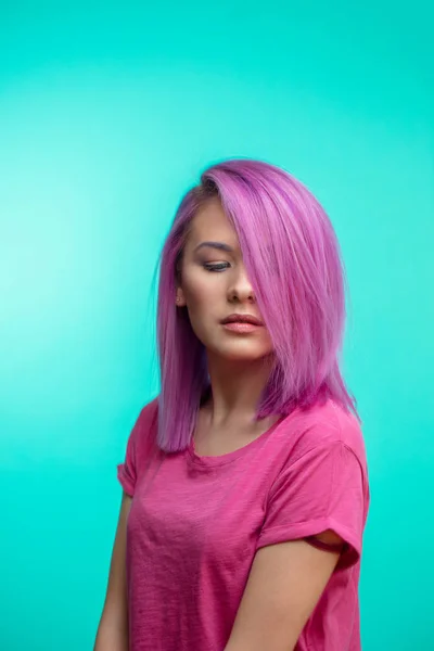 ピンク髪、青の背景にカジュアルなピンクの布に身を包んだ魅力的な女の子. — ストック写真