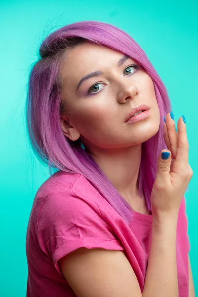 Attraktives Mädchen mit rosa Haaren, in lässigem rosa Tuch auf blauem Hintergrund gekleidet. — Stockfoto