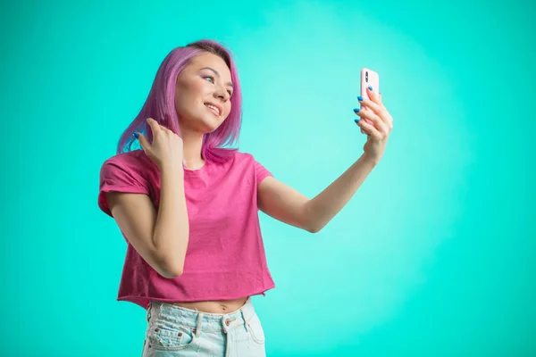 Mujer sonriente haciendo foto selfie en el teléfono inteligente aislado sobre un fondo azul — Foto de Stock