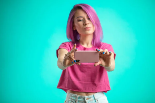 Mujer sonriente haciendo foto selfie en el teléfono inteligente aislado sobre un fondo azul — Foto de Stock