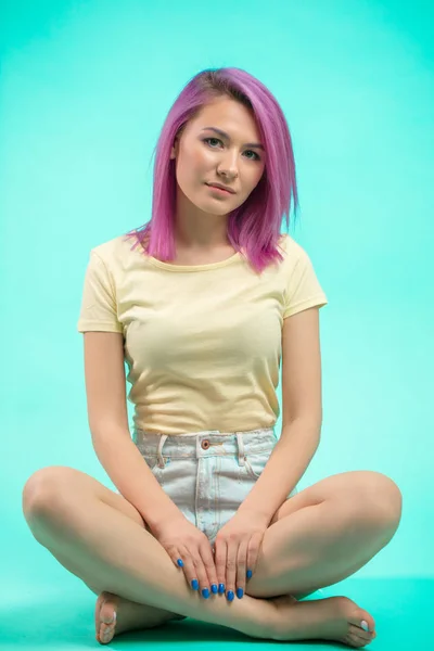 Μαθητή να κάθεται στο στούντιο. Νεαρή κοπέλα με ίσια ροζ μαλλιά που κάθεται στο πάτωμα. — Φωτογραφία Αρχείου
