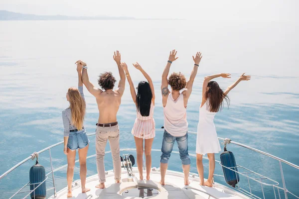 Widok z tyłu przyjaciół świętować na żaglówce w oceanie, ramiona podniesione. — Zdjęcie stockowe