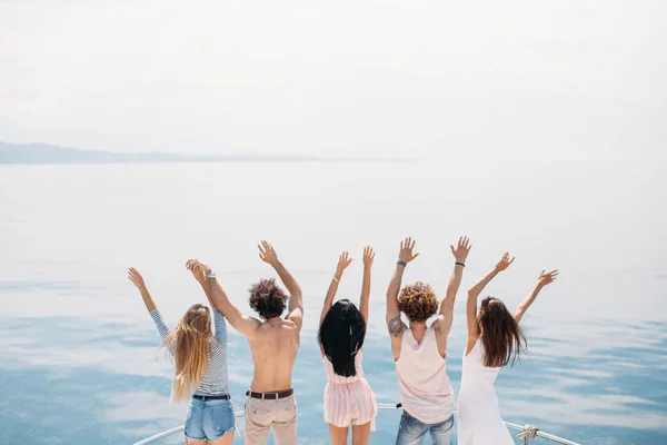 Vista posteriore di amici festeggiare in barca a vela in mare, braccia alzate. — Foto Stock