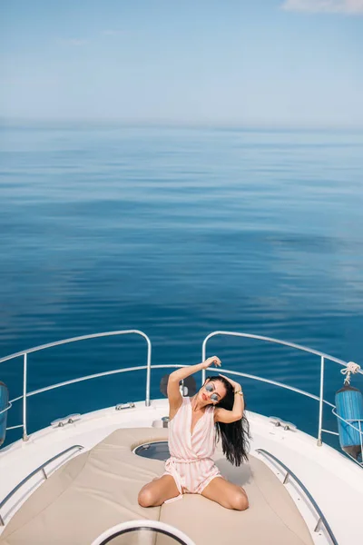 Retrato de morena do sexo feminino posando sobre fundo marinho no barco à vela — Fotografia de Stock
