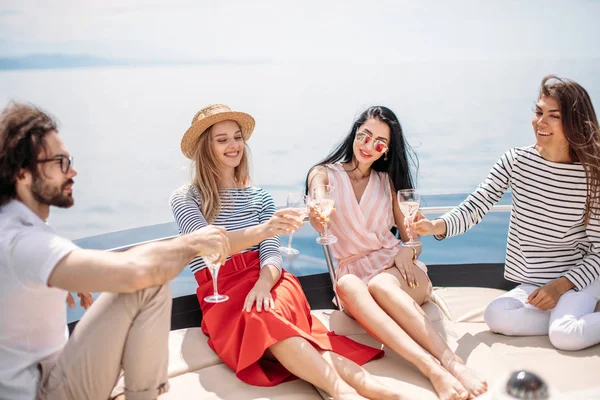 Felices amigos tintineando copas de champán y navegando en yate — Foto de Stock