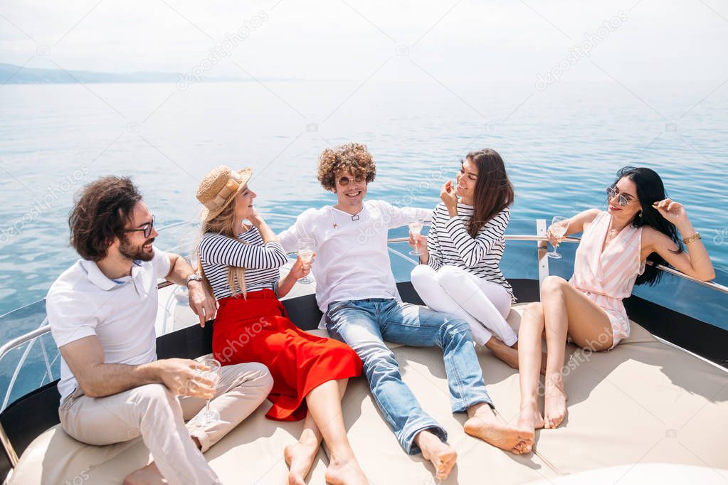 Friends having fun sailing on a yacht in sea, laughing, chatting and chilling