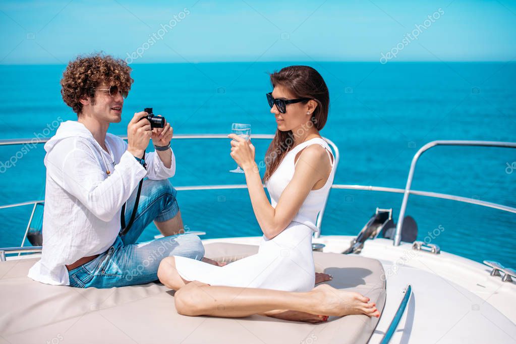 Attractive couple on the yacht. Young man is taking photo of his girlfriend