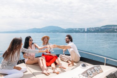 Mutlu arkadaşlar şampanya bardaklarını tokuşturup yatta yelken açıyorlar.