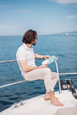 Deniz manzaralı lüks bir yatta sakallı genç bir adam..