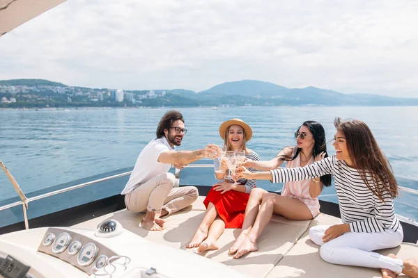 Šťastní přátelé cinkání sklenice šampaňského a plachtění na jachtě — Stock fotografie