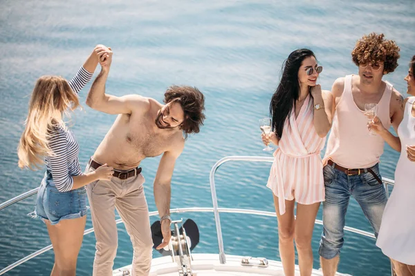 Meriristeily ja loma - nuoret, joilla on samppanjalasit veneessä tai jahdilla — kuvapankkivalokuva