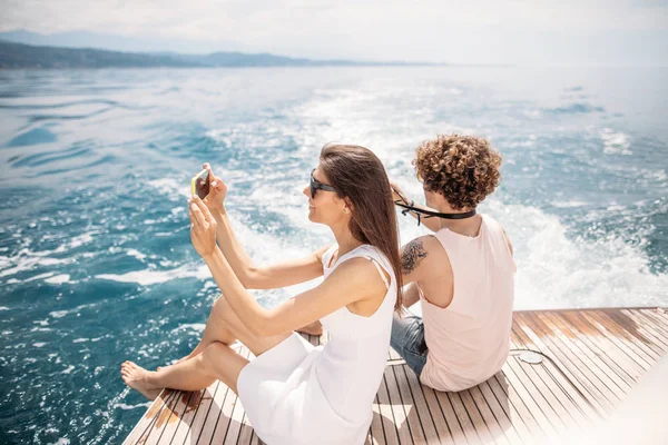 Young photographers taking picture of his girlfriend on seaboat — Stock Photo, Image