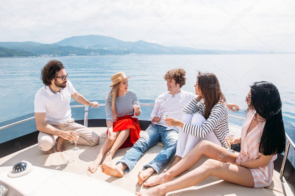 Friends having fun sailing on a yacht in sea, laughing, chatting and chilling