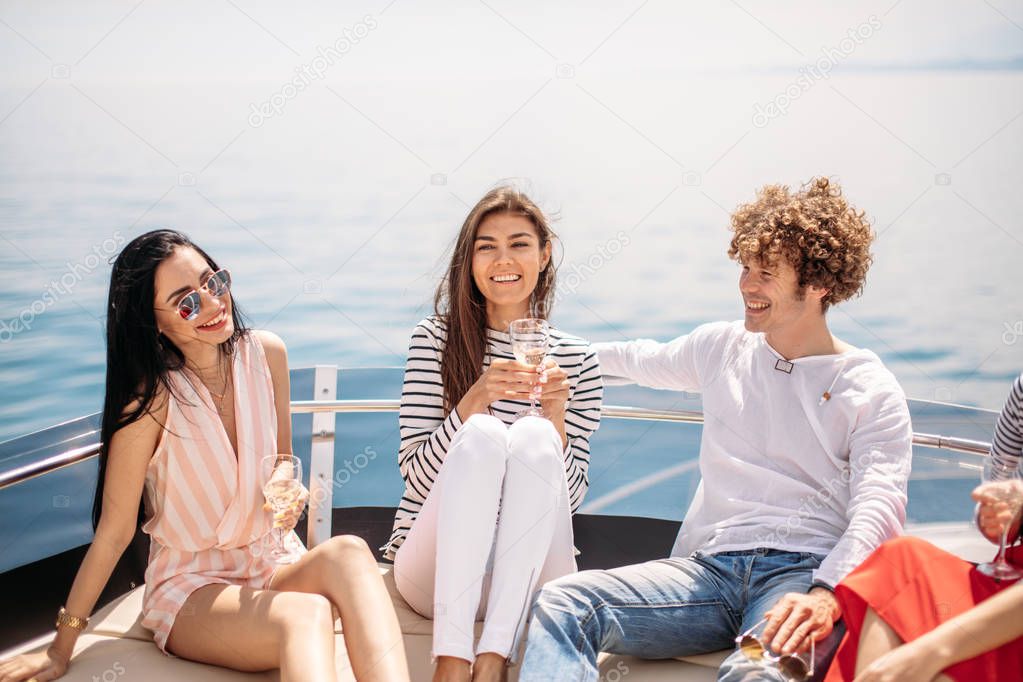 Friends having fun sailing on a yacht in sea, laughing, chatting and chilling