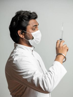 yan görünümü sportrait in Hint Doktor şırınga ile yakından enjeksiyon için hazırlanıyor