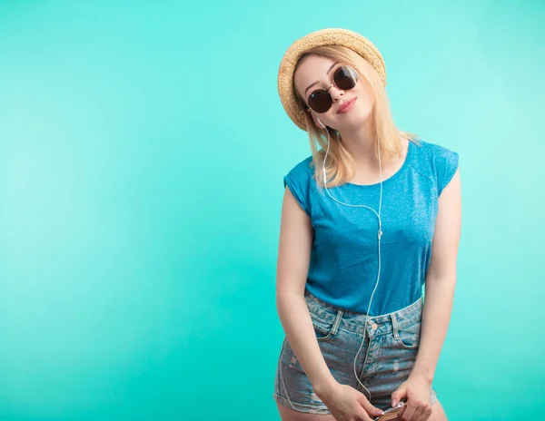 Chica de moda en gafas de sol con auriculares. fondo azul aislado . — Foto de Stock