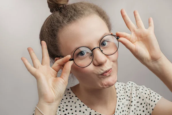 Смішна дівчина торкається її круглі окуляри — стокове фото