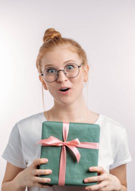 Sürpriz hoş kadın bir hediye tutarak ve kameraya bakıyor