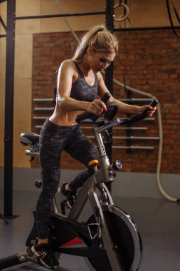 Bisiklet Eğitim cihazları üzerinde egzersiz yaparak çalışkan genç güzel kız