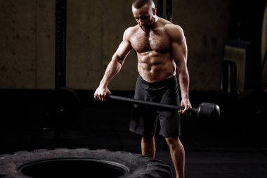 acımasız yakışıklı adam ile bir hamer traktör lastiği önünde duruyor