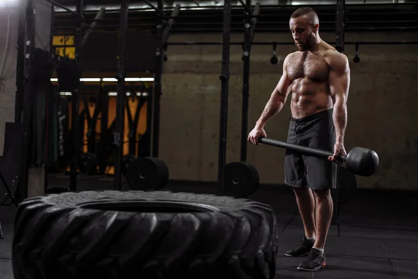 attractive well-built guy is building strength while cross fit training