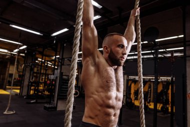 yan görünümü fotoğrafı kapatın. yükseltilmiş silah ve ip ile sakallı yakışıklı sporcu