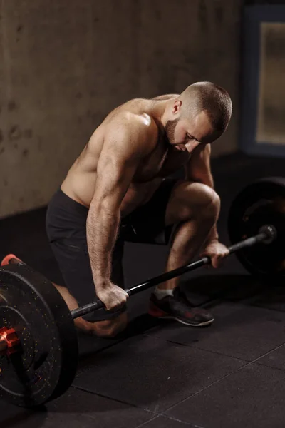 Goedgebouwde sterke man is werken met een zware barbell — Stockfoto