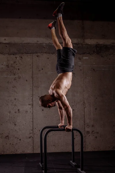 Ambitieuze sportieve jongeman uitvoeren van hand stand op P balken — Stockfoto