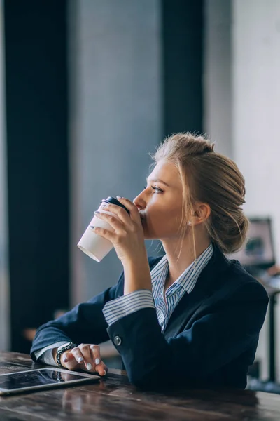 Элегантный офисный работник пьет чай в кафе с современным интерьером — стоковое фото